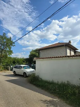 Spoljašnji izgled dvospratne kuće sa dvorišnim zidom i automobilom parkiranim pored puta. - image 3