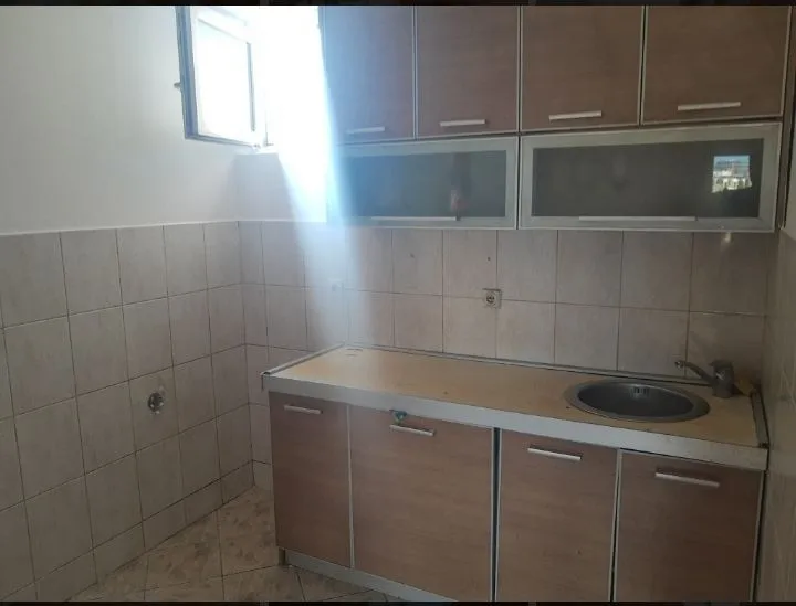 Jednostavna kuhinja sa drvenim elementima i ugrađenom sudoperom.