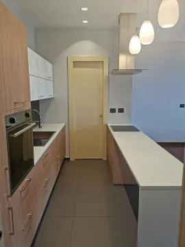 Modern narrow kitchen with wooden cabinets and white countertops. - image 5