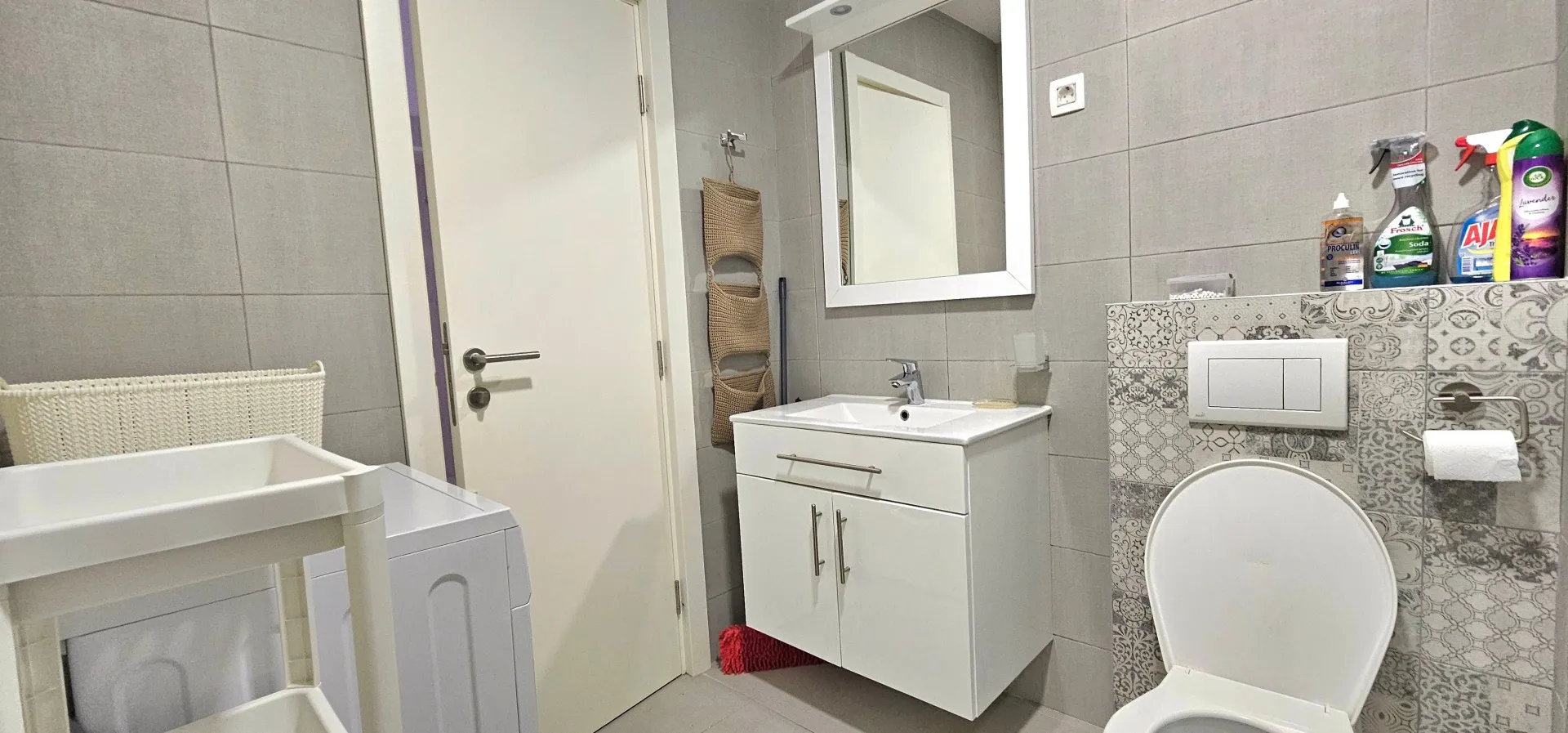 Modern bathroom with a washbasin, toilet, and washing machine.