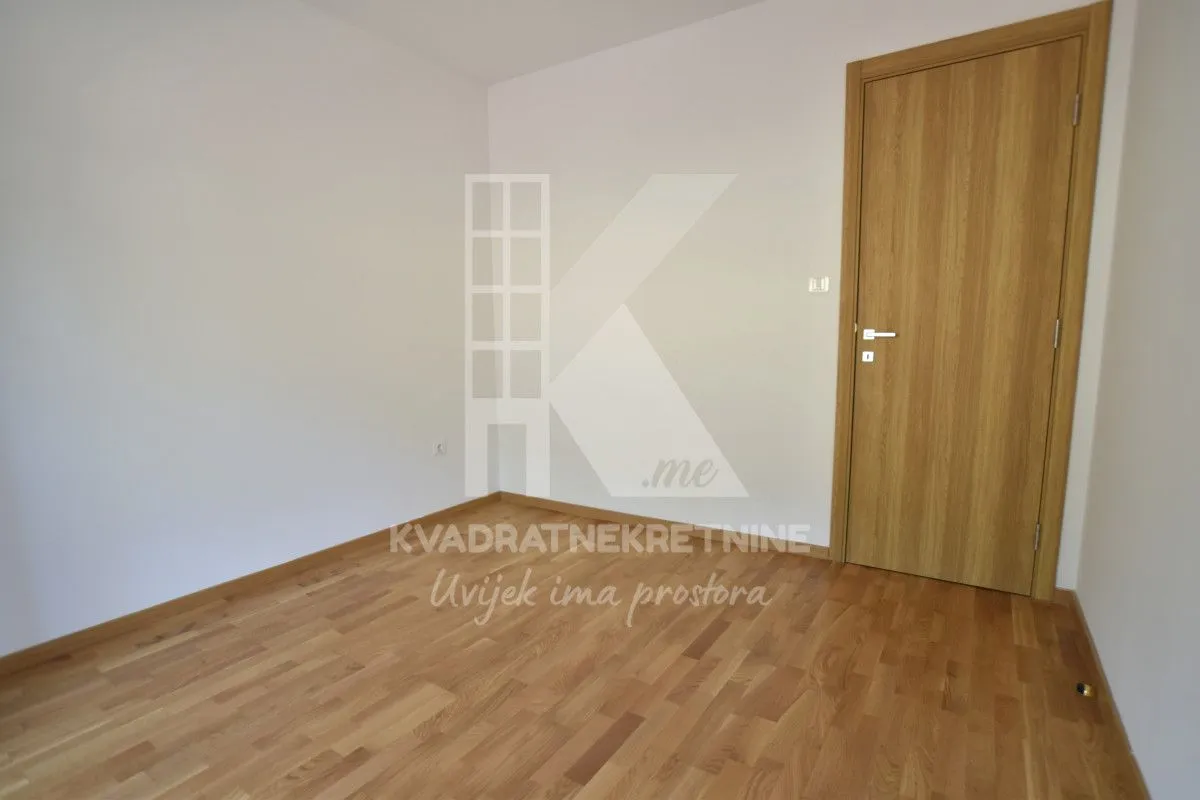 Prazna soba sa parketom i drvenim vratima.