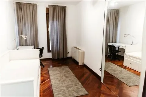 Bright bedroom with a single bed, a study desk, and a large mirror. - image 13