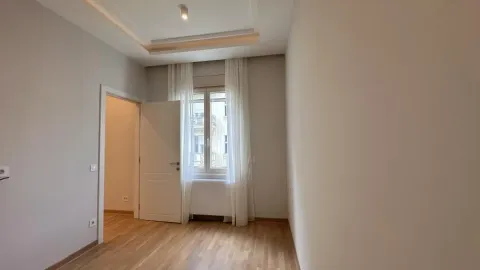 Prazna soba sa drvenim podom, belim vratima i prozorom sa zavesama. - image 9