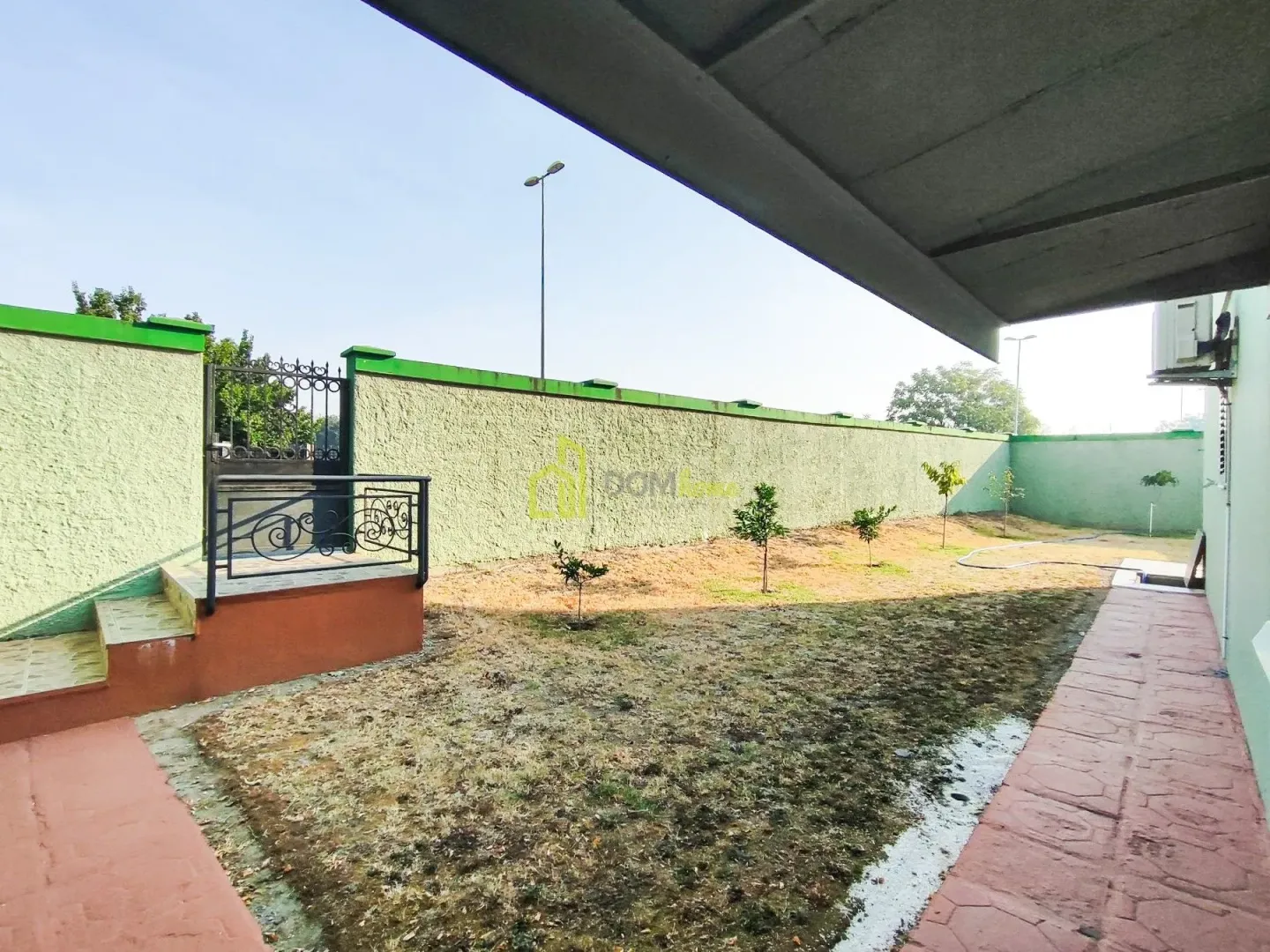 Enclosed courtyard with a walkway and landscaped greenery in front of the house.