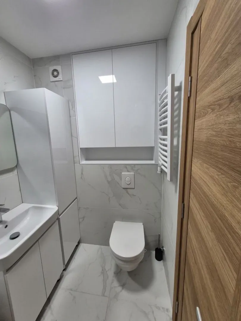 Moderne kupatilo sa bijelim elementima, umivaonikom i ugradnom wc šoljom.