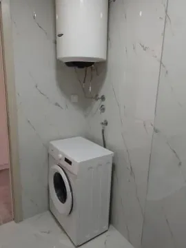 Part of a bathroom with a washing machine and water heater. - image 2