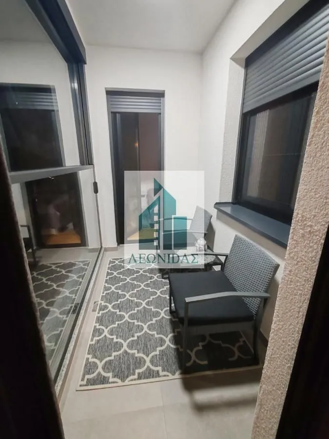 Small covered terrace furnished with outdoor seating and a rug.