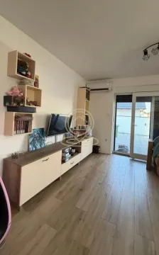 Dnevna soba sa TV komodom, policama i izlazom na terasu. - image 6
