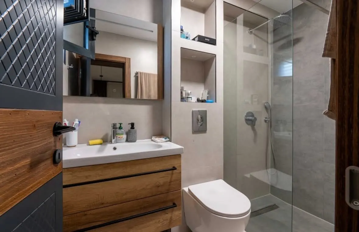 Modern bathroom equipped with a vanity unit, wall-hung toilet, and a glass shower enclosure.