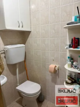 Manje kupatilo sa wc šoljom, belim ormarićem i zidnim pločicama. - image 9