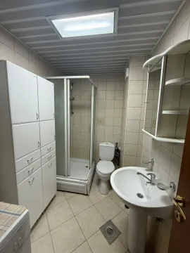 Kompaktno kupatilo sa tuš kabinom, umivaonikom, WC šoljom i bijelim ormarićima. - image 5