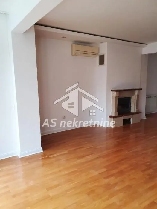 Living room with parquet flooring and a fireplace.