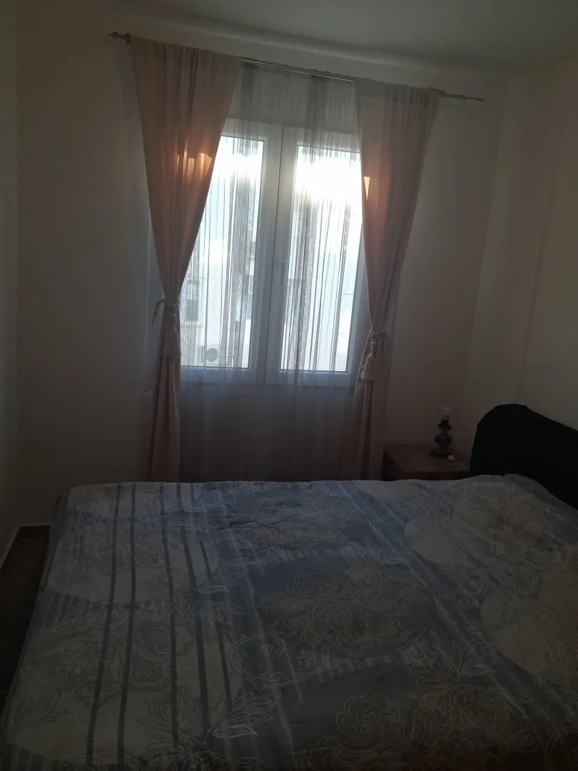 Bedroom with a double bed and a window with curtains.