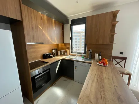 Modern equipped kitchen with wooden elements and a breakfast bar. - image 12