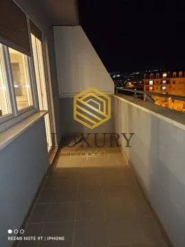 Illuminated balcony with a view of surrounding buildings at night. - image 2