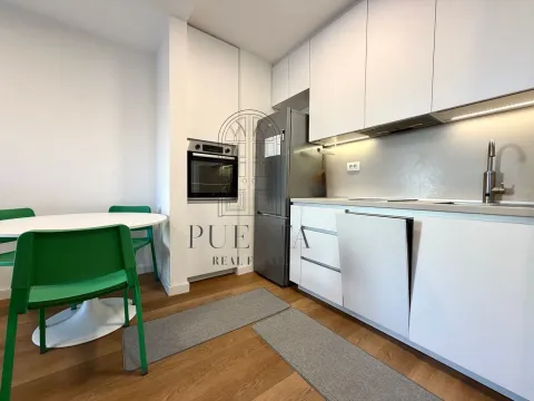 Modern white kitchen with built-in appliances and a dining table. - image 5