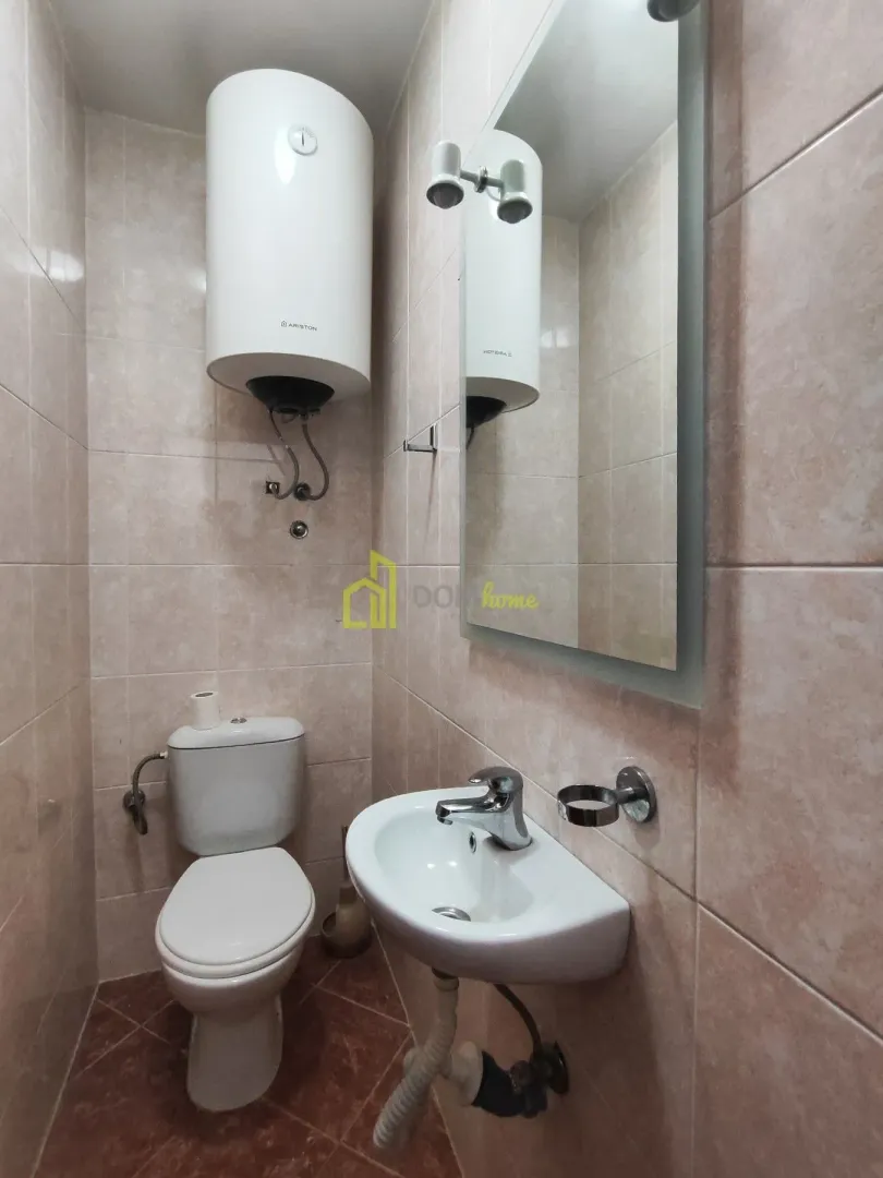 Small tiled bathroom with a toilet, washbasin, and water heater.