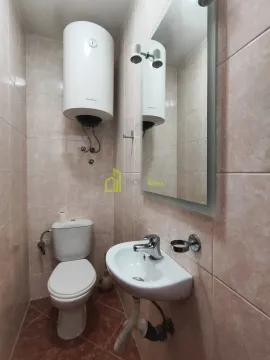 Small tiled bathroom with a toilet, washbasin, and water heater. - image 11