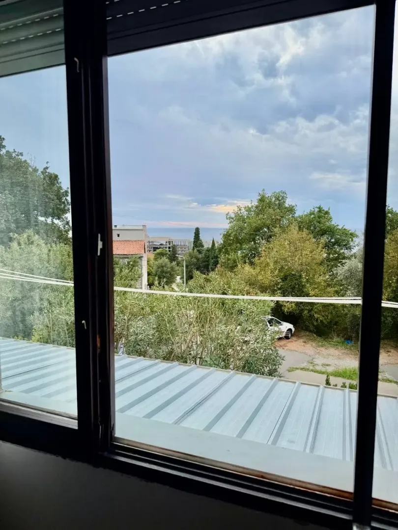 Pogled kroz prozor na okolno zelenilo i prirodu.