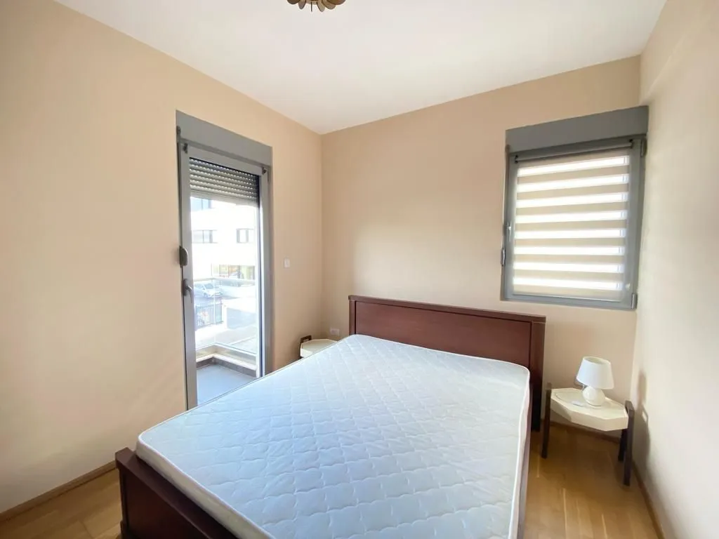 Bedroom with a double bed, nightstand, and a window with blinds.