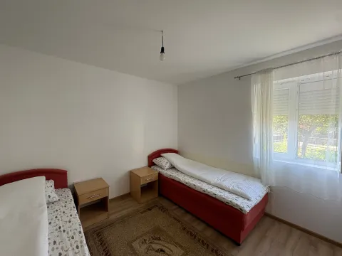 Spavaća soba sa dva kreveta, noćnim stolićima i prozorom. - image 8