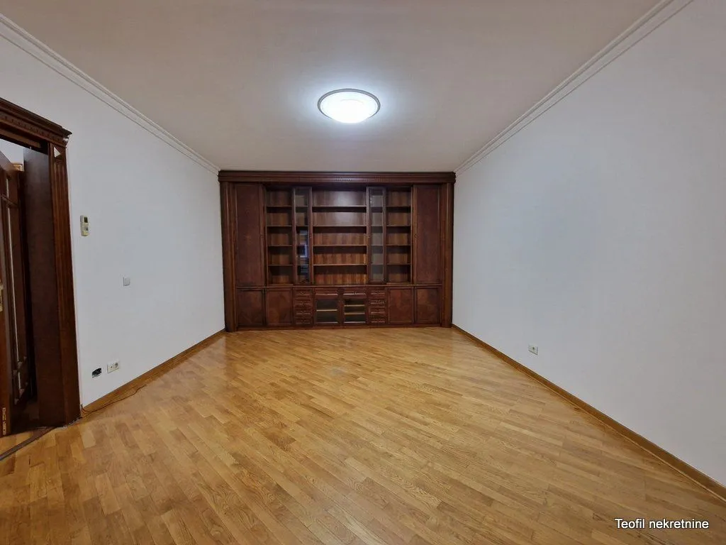 Empty living room with a wooden display cabinet and hardwood flooring.