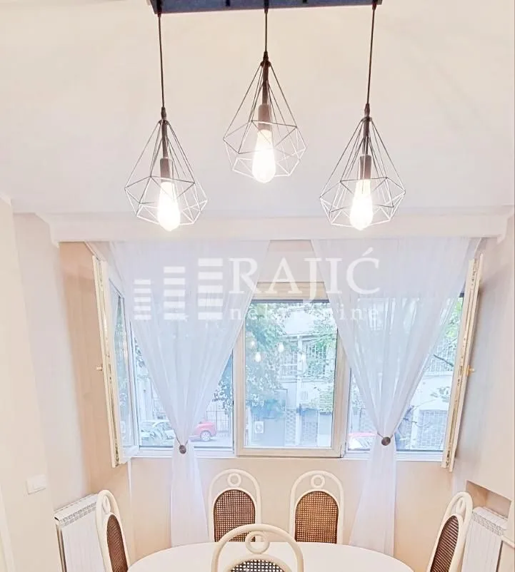 Dining room with a white table, chairs, and modern pendant lights.