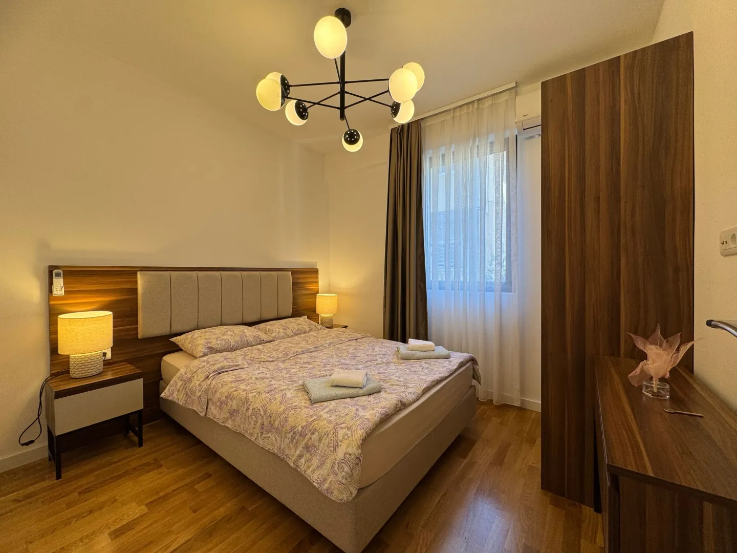 Furnished bedroom with a double bed, nightstands, and a wooden wardrobe.