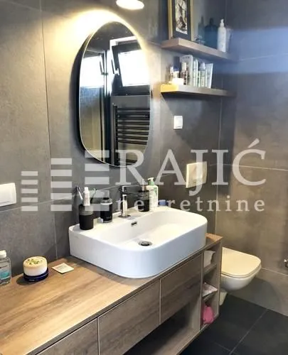 Modernly equipped bathroom with a washbasin, mirror, and toilet.