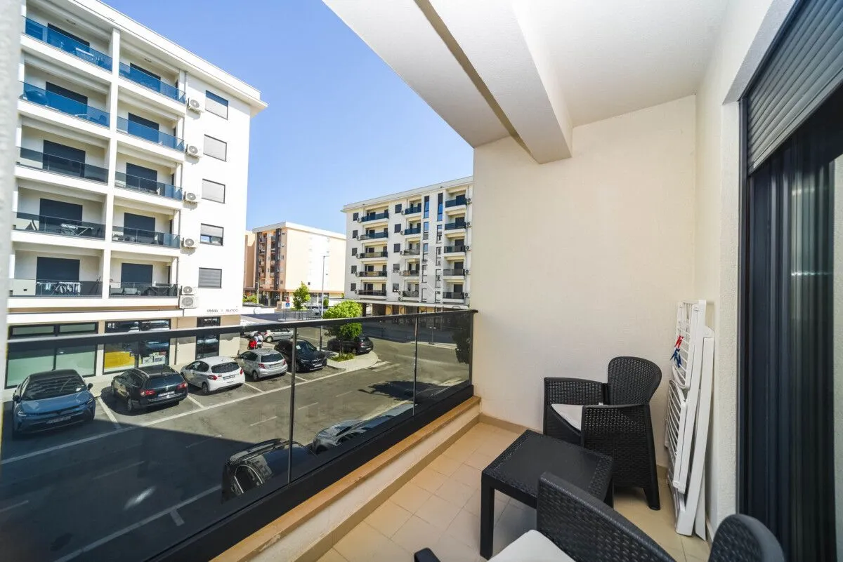 Furnished balcony with outdoor seating and a view of the street and buildings.