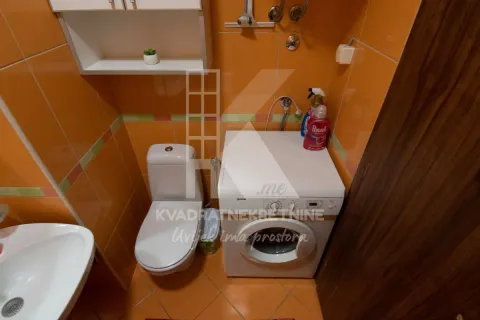 Kompaktno kupatilo sa narandžastim pločicama, toaletom, umivaonikom i veš mašinom. - image 16