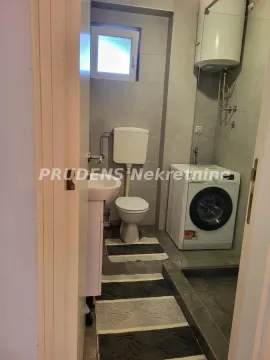 Small bathroom with a shower cabin, toilet, washbasin, and washing machine. - image 6
