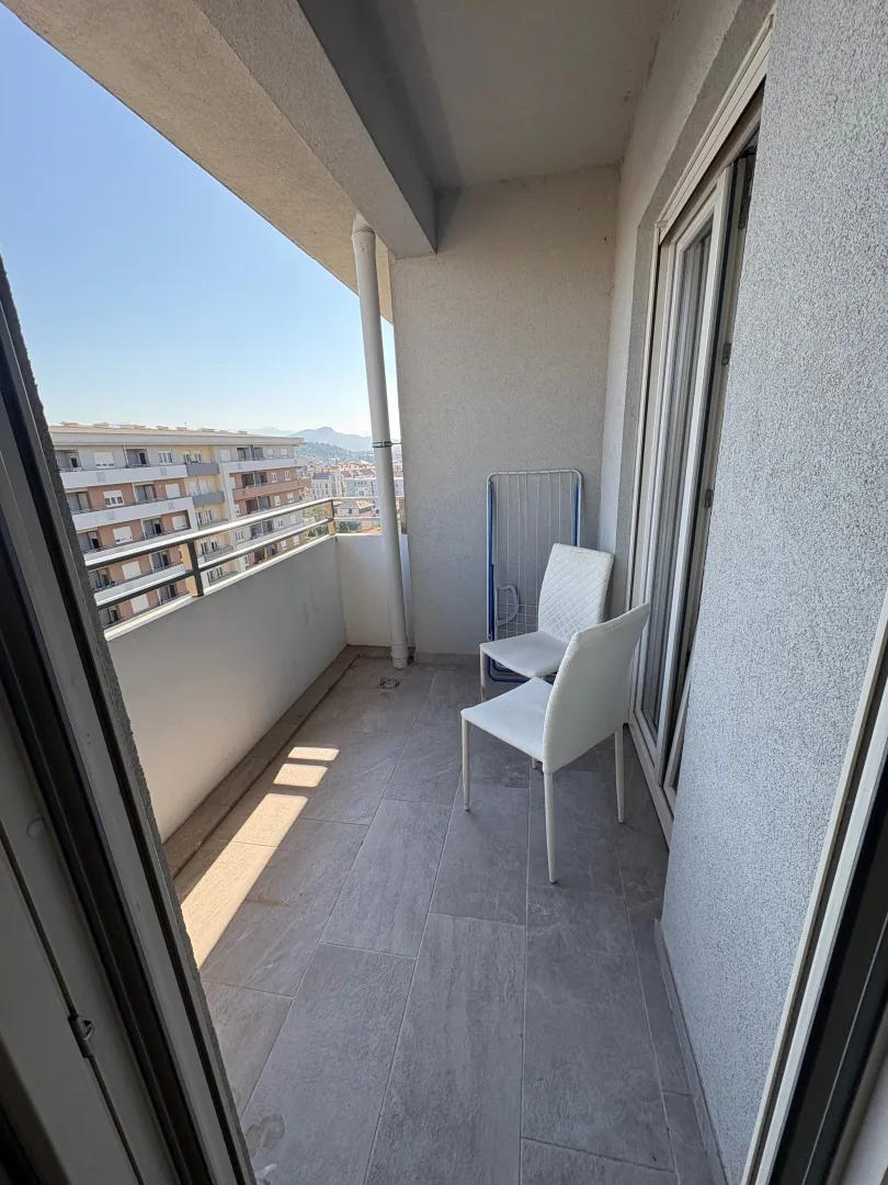 Covered balcony with chairs and city view.