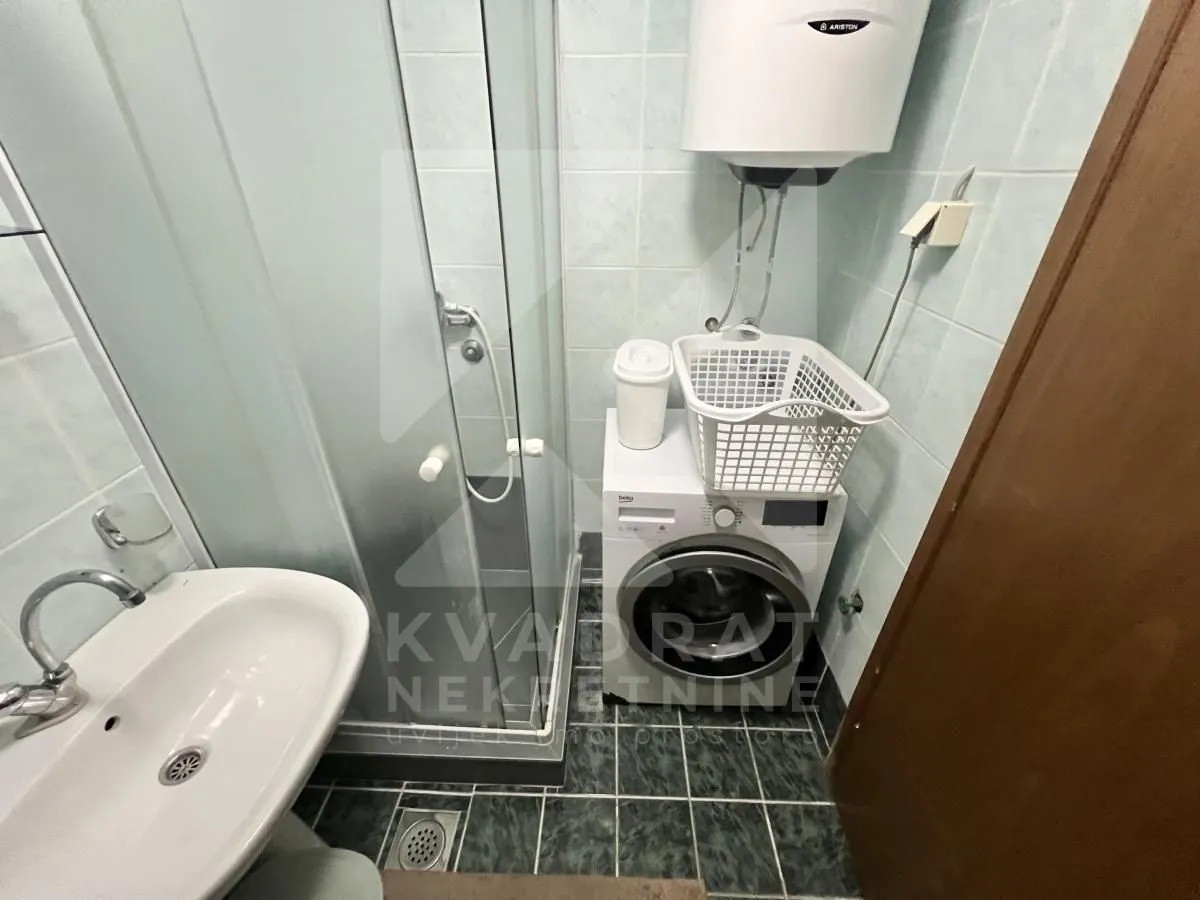 Bathroom with a shower cabin, washbasin, and washing machine.
