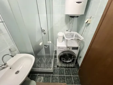 Bathroom with a shower cabin, washbasin, and washing machine. - image 9