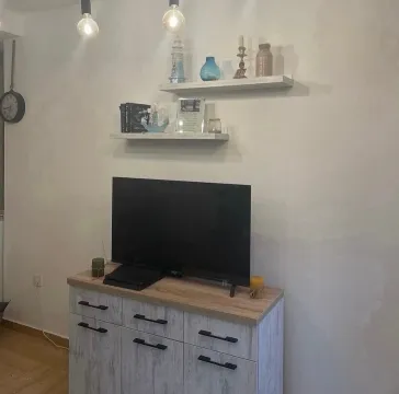 Living room with a television and wall shelves. - image 4