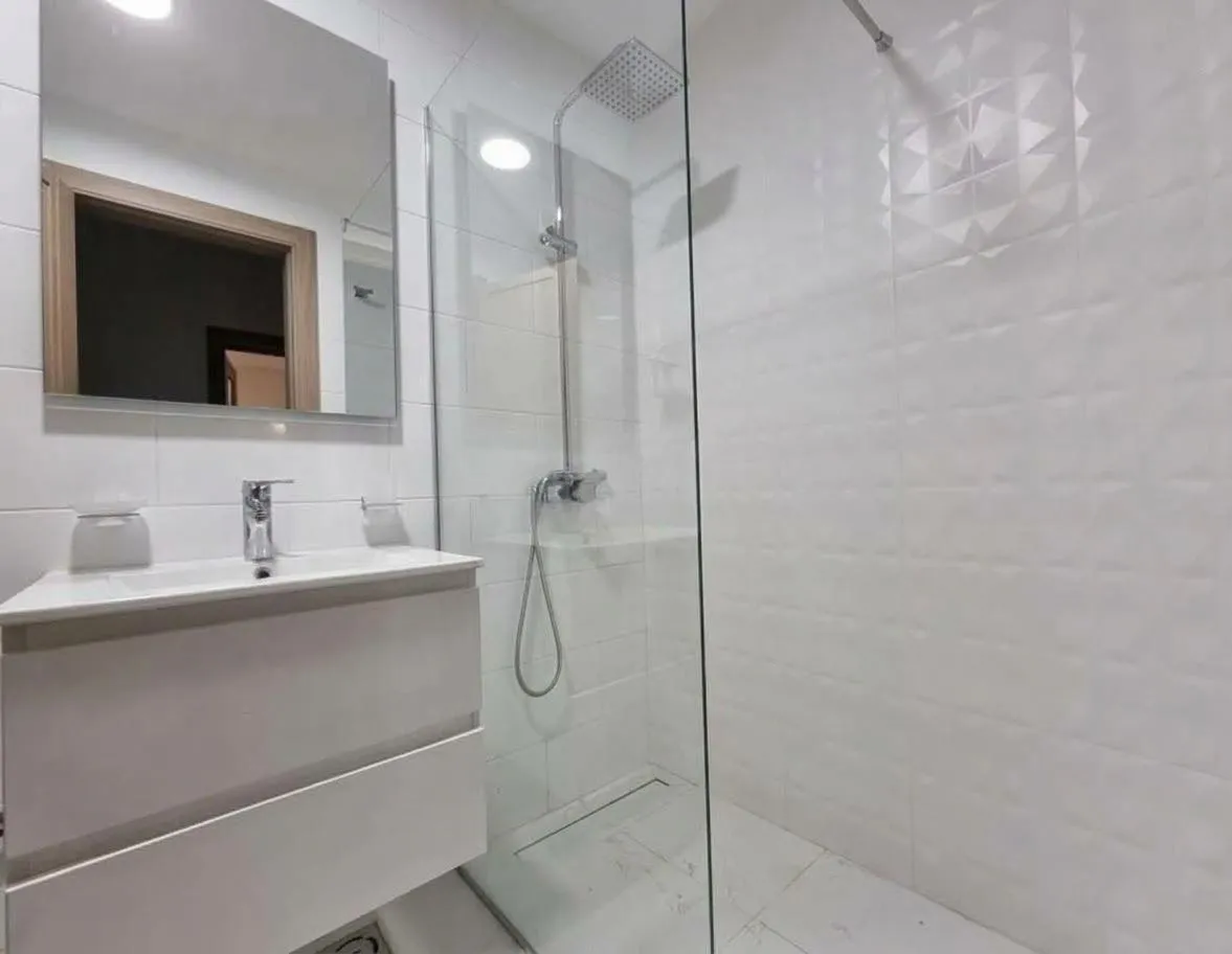Modern bathroom with a sink and shower enclosure.