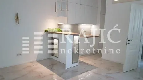 Modern white kitchen with a bar counter and built-in lighting.