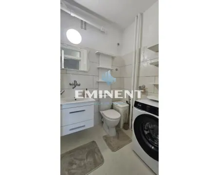 Small bathroom with a washbasin, toilet, shelves, and a washing machine. - image 13