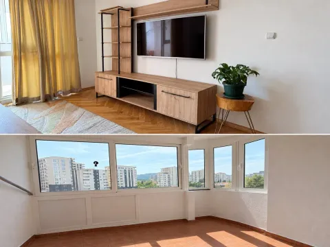 Dnevni boravak sa drvenom komodom i televizorom, kao i zastakljena terasa sa pogledom na grad. - image 2