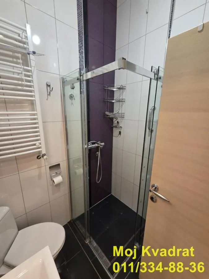 Manje kupatilo sa tuš kabinom, wc šoljom i radijatorom za peškire.