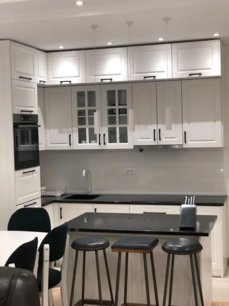 Modern white kitchen with black countertops and a breakfast bar.