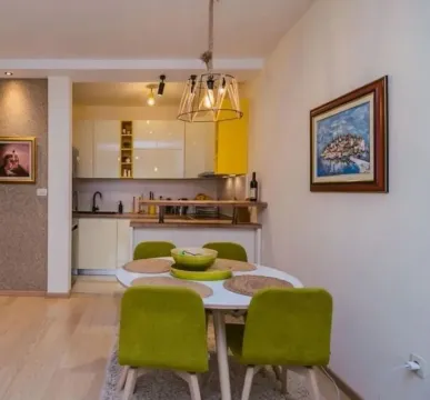 Dining area with a table and green chairs overlooking the kitchen. - image 3