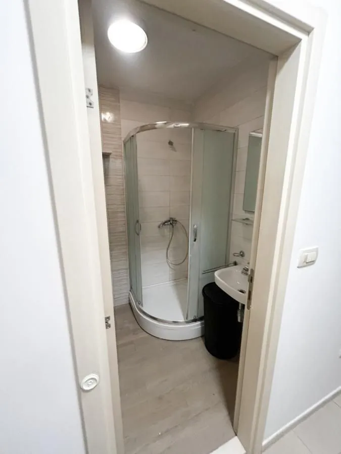 Pogled kroz vrata na kupatilo sa tuš kabinom.