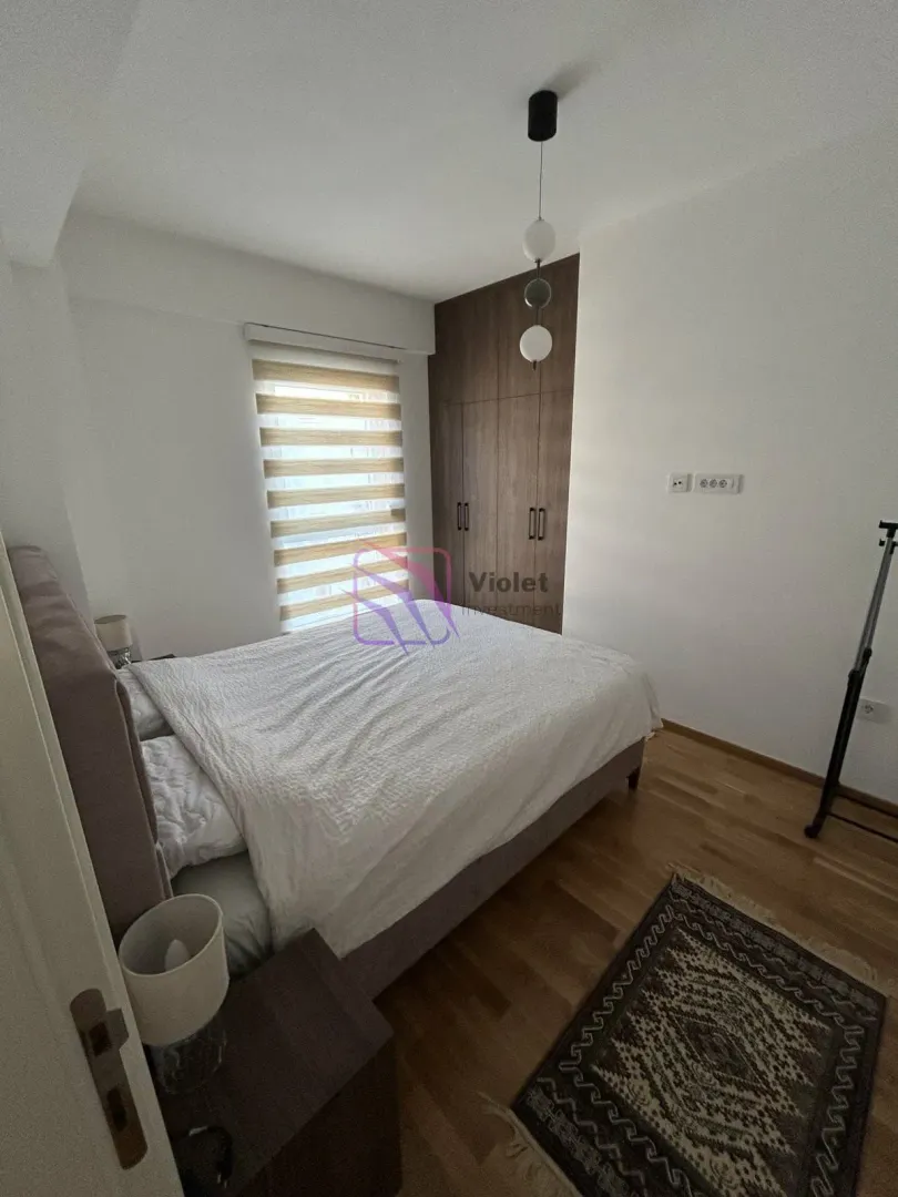 Namještena spavaća soba sa bračnim krevetom, ormarom i prozorom.