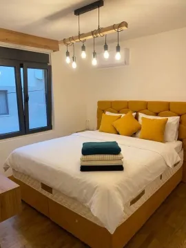 A decorated bedroom with a yellow double bed and a modern chandelier. - image 7