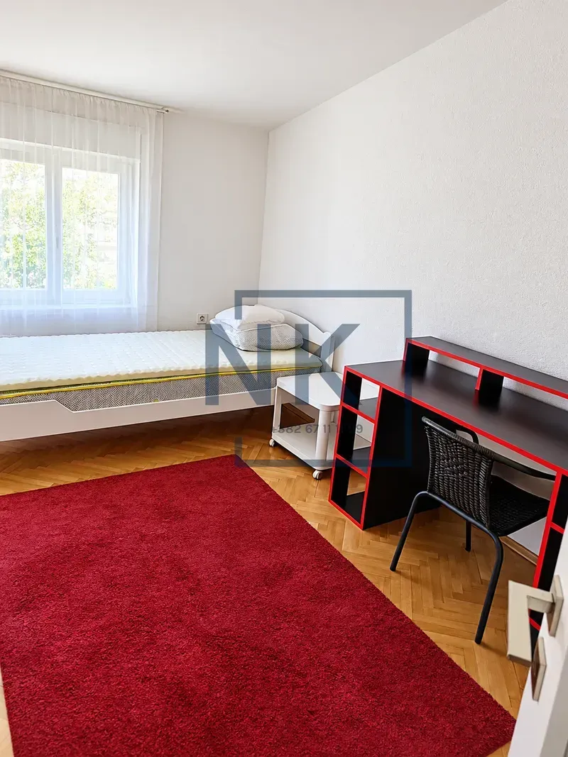 Bedroom with a bed, a desk, and a red rug.