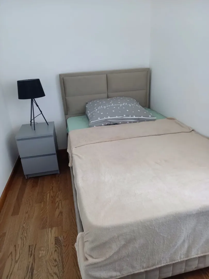 Manja spavaća soba sa krevetom i noćnim stočićem.