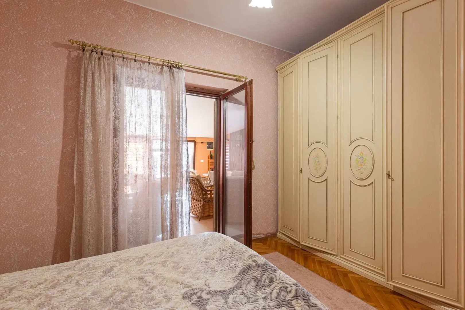 Spavaća soba sa velikim garderoberom, krevetom i izlazom na terasu.