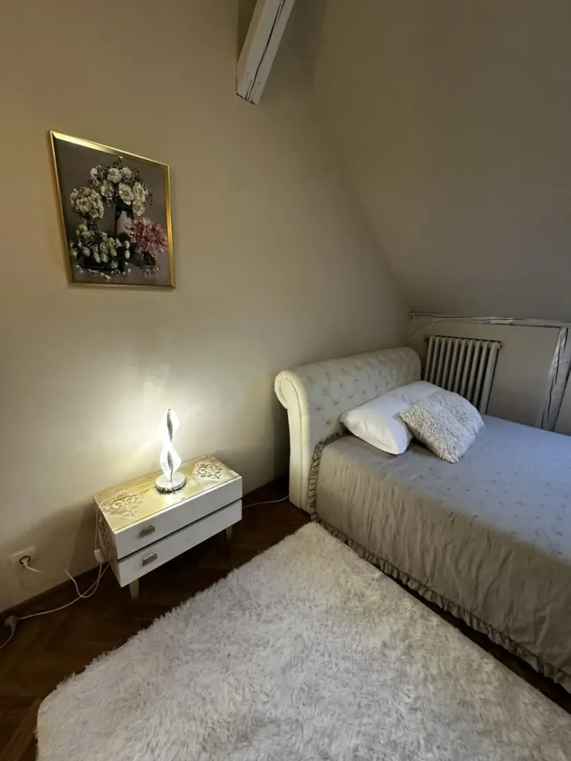 Small bedroom with a bed, nightstand, and a painting on the wall.